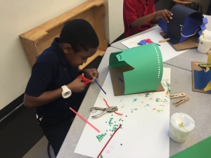 La'Derrian, 2nd grade, uses the materials carefully as he creates his art piece.